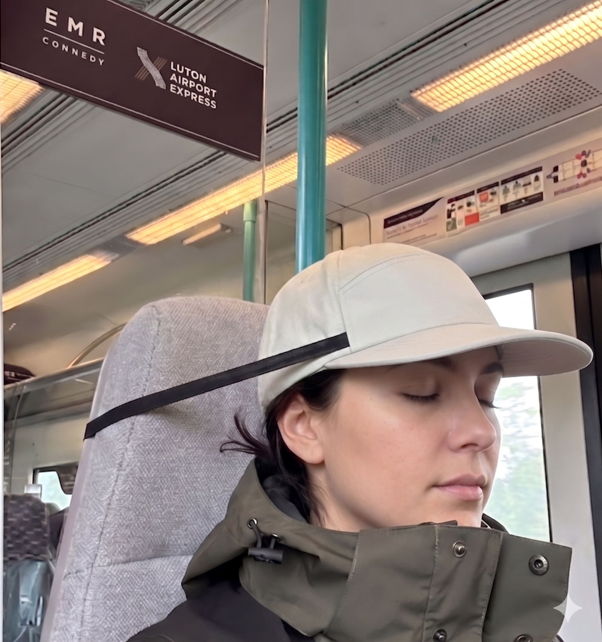 Person wearing the Dreaming Cap and sleeping comfortably on a train with her head hold upright .